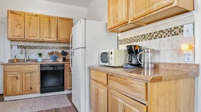 a kitchen with wooden cabinets and a white refrigerator at Midtown Flight Deck: 2BR Gem in Reno