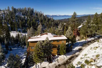 a house on a snow covered hill with trees at Tall Pine Chalet in Stateline