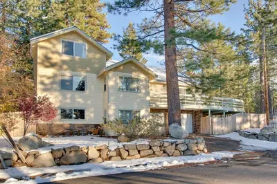 a house with a stone fence in front of it at Sequoia Chalet in Stateline