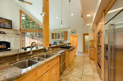 a large kitchen with a sink and a fireplace at Lodgepole Pine Chalet in South Lake Tahoe