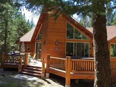 a log cabin with a porch and a tree at Lodgepole Pine Chalet in South Lake Tahoe