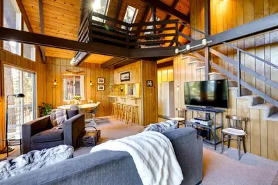 a living room with a couch and a tv and stairs at 3 Mi to Big Trees State Park Cabin with Deck in Arnold