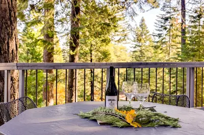 a bottle of wine sitting on a table with glasses at 3 Mi to Big Trees State Park Cabin with Deck in Arnold