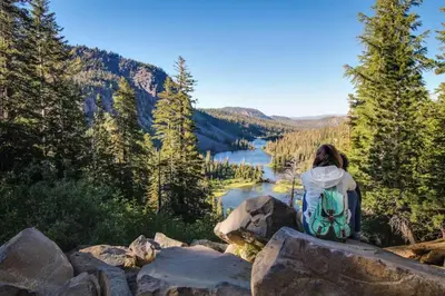 a woman sitting on a rock overlooking a lake at Creekhouse 1362 in Mammoth Lakes