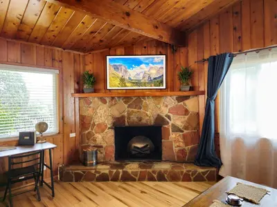 a living room with a stone fireplace in a house at Yosemite Gateway Cottage - King Suite - Mountain Views in Oakhurst