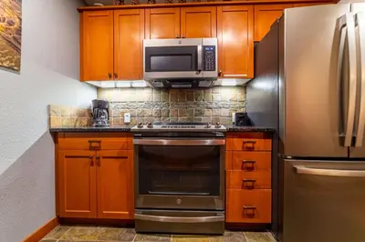 a kitchen with wooden cabinets and a stainless steel refrigerator at Luxurious Remodeled Village Oasis in Mammoth Lakes