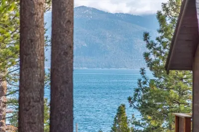 a view of a body of water through some trees at Coziest Cabin in Tahoe w Stone Fireplace Comfy Beds Close to Slopes & Lake in Carnelian Bay