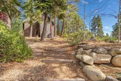 a log cabin with a pile of rocks in front of a house at Coziest Cabin in Tahoe w Stone Fireplace Comfy Beds Close to Slopes & Lake in Carnelian Bay