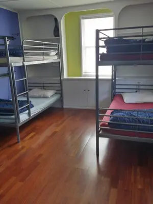 a room with three bunk beds and a wooden floor at Yosemite International Hostel in Groveland