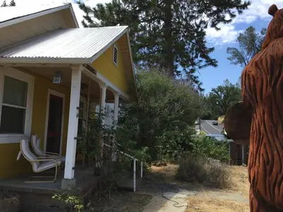 a house with a bear statue in front of it at Yosemite International Hostel in Groveland