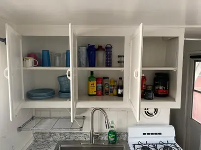 a kitchen with white cabinets with dishes and a sink at Midtown Charm: 1BR Urban Pad in Reno