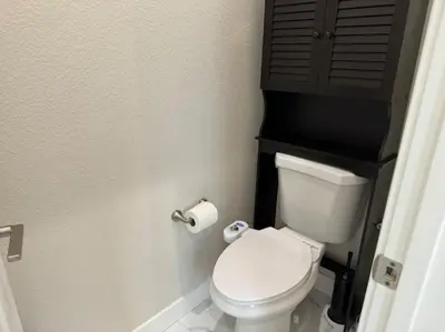 a bathroom with a white toilet with a brown cabinet at Brand New South Sacramento Home in Sacramento