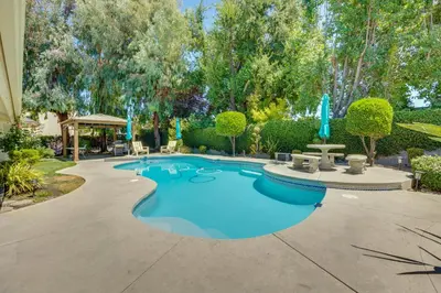 a swimming pool in a yard with trees at Billiards and Private Pool Bright Clovis Home! in Clovis