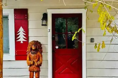 a bear statue in front of a house with a red door at Red Door Cottage Fireplace bbq 12 mi to Yosemite in Oakhurst