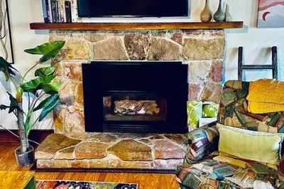 a living room with a stone fireplace with a couch at Orange Door Electric Fireplace bbq in Oakhurst