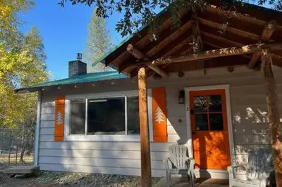 a small white house with a bench in front of it at Orange Door Electric Fireplace bbq in Oakhurst