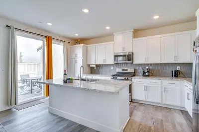 a kitchen with white cabinets and a large window at Newly Built Tracy Home with Backyard and Pool Access! in Tracy