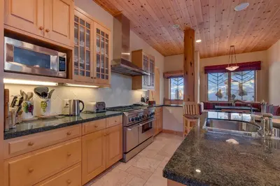 a large kitchen with wooden cabinets and a sink at Sundance Lodge -Mountain Home w Views of Palisades - Ski Shuttle, Pets okay! in Olympic Valley