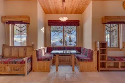 a living room with a table and benches and windows at Sundance Lodge -Mountain Home w Views of Palisades - Ski Shuttle, Pets okay! in Olympic Valley