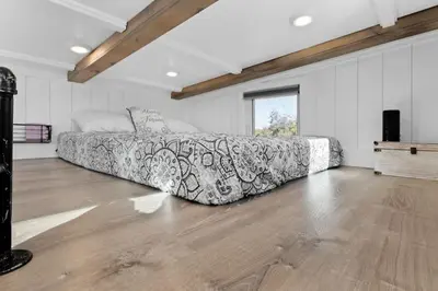 a bedroom with a couch in a room with a wooden floor at Tiny Home | Lewis Ranch 1 in Lindsay