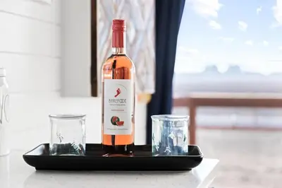 a bottle of wine on a tray with two glasses at Tiny Cargo Home South in Tulare