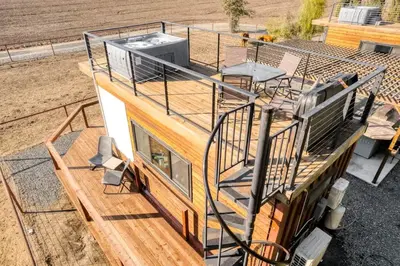 a house with a balcony on top of it at Tiny Cargo Home South in Tulare