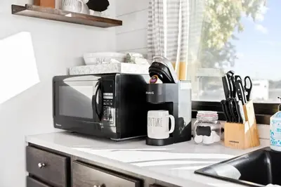 a microwave sitting on a kitchen counter next to a sink at Tiny Cargo Home South in Tulare