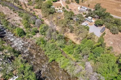 an aerial view of a forest with a river at Tiny River House in Three Rivers