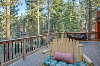 a wooden rocking chair on a deck with trees at 4 Mi to Slopes Family-Friendly Stateline Home! in Stateline