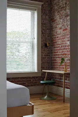 a bedroom with a bed and a desk and a brick wall at The Jesse Hotel & Bar in Reno