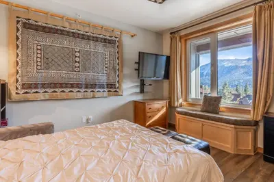 a bedroom with a bed and a window and a television at Juniper Springs Lodge #412 - Luxury Ski in Ski out! 2 Bedroom in Mammoth Lakes