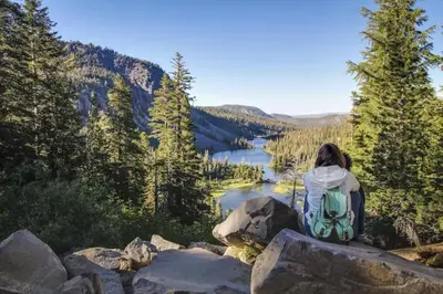 a woman sitting on a rock overlooking a lake at Horizons 4 131 in Mammoth Lakes
