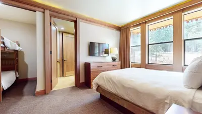 a bedroom with a bed and a tv and windows at Obsidian #1 home in Mammoth Lakes