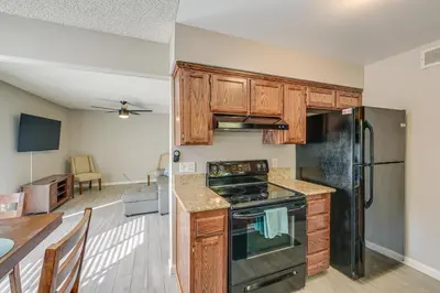 a kitchen with wooden cabinets and a black appliances at Cozy Fresno Condo with Balcony and Pool Access in Fresno