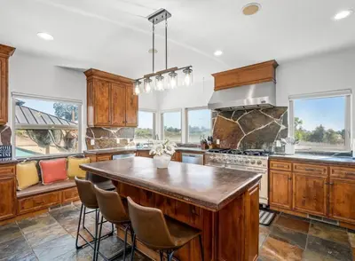 a large kitchen with a large wooden island with chairs at Luxury 4 Acre Estate - Pickleball, Pool, Hot Tub! in Lockeford