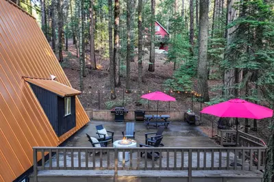 an aerial view of a deck with tables and pink umbrellas at 3 Mi to Calaveras Big Trees Cabin with Fire Pit! in Arnold