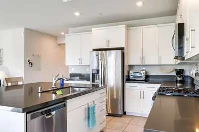 a kitchen with white cabinets and a stainless steel refrigerator at Stylish Lodi Wine Country Retreat with Private Patio in Lodi