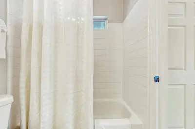 a white shower curtain in a bathroom with a tub at A Taste of Tahoe in Tahoe Vista