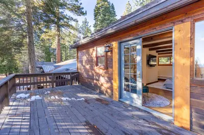 a wooden cabin with a large glass door on a deck at Hideaway in the Highlands - 4BR, Pet Friendly w Hot Tub - Minutes from the Lake & Tahoe City in Tahoe City