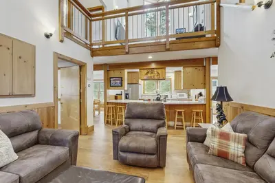 a living room with a couch and chairs and a kitchen at The Mountain House in Soda Springs