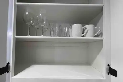a white cabinet with glasses and wine glasses at Entire Modern House with King bed & 65inTV in Carmichael