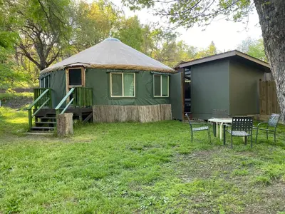 a green yurt with a table and chairs in a yard at Seven Circles Lodge&Retreat in Badger
