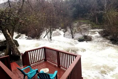 two chairs sitting on a deck overlooking a river at River Retreat Cabin in Three Rivers - near SNP in Three Rivers