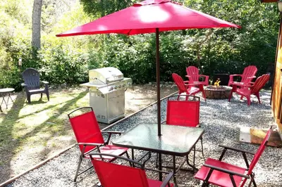 a group of red chairs and a table with an umbrella at River Retreat Cabin in Three Rivers - near SNP in Three Rivers