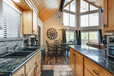 a kitchen with wooden cabinets and a large window at Serene Cabin Retreat Between Murphys and Arnold in Murphys