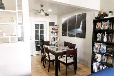 a dining room with a table and chairs and a book shelf at SunHouse 1410sqft BBQ 3xTVs Pets W/D Backyard in Sacramento