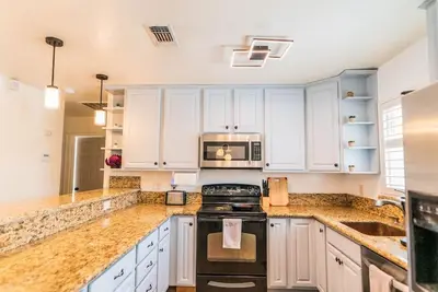a kitchen with white cabinets and a stove top oven at Arden Family Home BBQ Big Kitchen Backyard Pet W/D in Sacramento