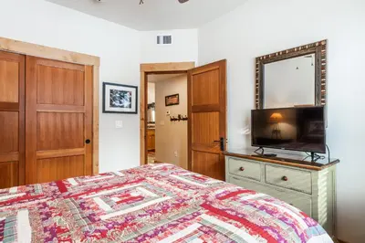 a bedroom with a bed and a mirror and a television at Upscale 4 Bed, 3 Bath at the Woodwinds with Amazing Mountain Views and Golf Course Access and private hot tub and garage sleeps 10 in Mammoth Lakes