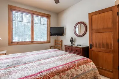 a bedroom with a bed and a flat screen tv at Upscale 4 Bed, 3 Bath at the Woodwinds with Amazing Mountain Views and Golf Course Access and private hot tub and garage sleeps 10 in Mammoth Lakes