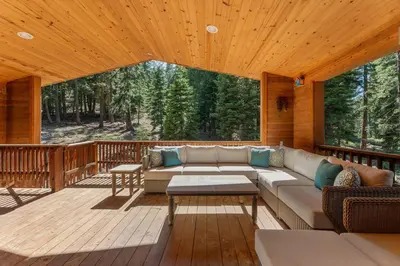 a living room with a couch on a wooden deck at The Pinecrest Retreat- 10 mins to NorthStar! Hot Tub, Large Deck, Views, and Games in Tahoe Vista